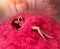 Fantasy woman princess lies in skirt lush pink neon bright color dress ball gown. Queen girl fashion model posing