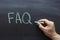 FAQ, frequently asked questions abbreviation, written on a blackboard in green chalk