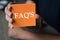 Faq`s word on an orange note paper, Business Concept