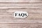 FAQS of the word on paper. frequently asked questions concept. Words of FAQS on a wooden background