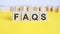 faqs word on wooden building blocks lying on the yellow table, concept