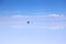 In the far horizon a man and an off road vehicle in the middle of an immense light blue plain. Adventure in Bolivia Uyuni salty de