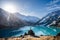 Far shot of a man standing on a boulder on a vantage point over a mountain lake