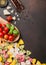 Farfalle multicolor italian luxury pasta with parmesan cheese and tomatoes, salt and pepper with oil on brown background