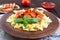 Farfalle pasta in a ceramic bowl, serve with ketchup, fresh tomatoes, sausage in tomato sauce