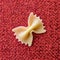 Farfalle Pasta Closeup on red textile background