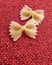 Farfalle Pasta Closeup on red textile background