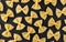 Farfalle pasta pattern on black background, top view, flat lay texture