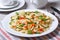 Farfalle pasta with slices of vegetables, cheese closeup