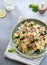 Farfalle pasta with spinach and mushrooms in a green ceramic plate.