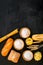 Farinaceous food. Fresh bread and raw pasta near flour in bowl and wheat ears on black background top view copy space