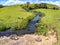 Farm field, trees and stream with waterfall