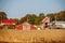 Farm and outbuildings and half fallen down barn with agricultural trucks in Autumn with cornfield in foreground