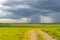 The farm road and the oncoming rain wall in the background