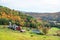 Farm in a rolling rural landscape on a cloudy autumn day. Beautiful autumn colours.