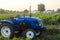 A farm tractor without a driver stands on a farm field at sunset. Subsidizing and supporting farms, modernization of technical