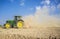 Farm tractor preparing dusty soil affected by drought