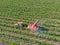 Farm tractor spraying pesticides & insecticides herbicides over green vineyard field