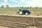 A farm tractor is standing on the field. Preparing the land for planting future crop plants. Cultivation of soil for planting.