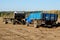 Farm trailer and truck stand on plowed field. Preparation for planting crops. Clear blue sky on a sunny day