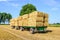 Farm trailers fully loaded with piled bales of straw