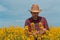 Farmer agronomist checking up on development of rapeseed crops in field, man working on plantation