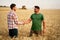 Farmer and agronomist shaking hands in wheat field after agreement. Agriculture business contract concept. Corporate