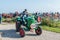 Farmer in blue cap and jeans on green tractor