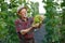 Farmer with bunch of grapes in hands standing in modern orchard