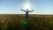 Farmer businessman with raised hands walks through the wheat field at sunrise