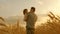 Farmer carries a little daughter in his arms through a field of wheat. happy child and father are playing in field of