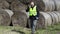 Farmer checking hay bales and talking on smartphone