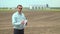 Farmer checks the field before wheat. Modern industrial plant on the background