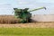 A farmer combining a field of corn in his John Deere combine harvester