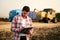 Farmer controls loading wheat from harvester to grain truck. Driver holding clipboard, keeping notes, cargo counting