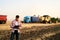 Farmer controls loading wheat from harvester to grain truck. Driver holding clipboard, keeping notes, cargo counting