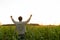 Farmer in a corn field raises his hands up, his head raised to the sky, enjoying his success
