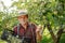 Farmer with crate of green apples standing in modern orchard