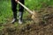 Farmer digging the soil with the shovel, young adult man with rubber boots