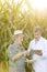 Farmer discussing with scientist digital tablet against corn crops at farm