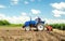 Farmer drives a tractor with a milling machine. Loosens, grind and mix soil on plantation field. Field preparation for new crop