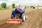 Farmer drives a tractor with a milling machine. Loosens, grind and mix soil on plantation field. Loosening surface, cultivating