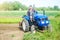 A farmer drives a tractor while working on a farm field. Loosening surface, cultivating the land. Farming, agriculture