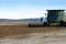 Farmer driving combine to harvest field of soybeans for food and other products.