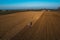 farmer driving a crawler tractor ploughing power harrowing surface crust, breaking cods to seeding of plants on dry soil