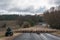 Farmer driving herd of sheep with two working shepherd dogs on countryside road