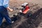 Farmer driving small tractor for soil cultivation and potato planting. Spring preparation