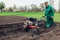 Farmer driving small tractor for soil cultivation and potato planting. Spring preparation