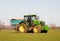 Farmer driving a tractor and sprinkling fertiliser on a field.