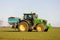 Farmer driving a tractor and sprinkling fertiliser on a field.